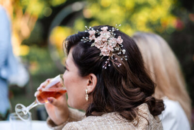 Invitée au chignon orné d'une parure florale dorée dégustant un verre de rosé lors d'une réception