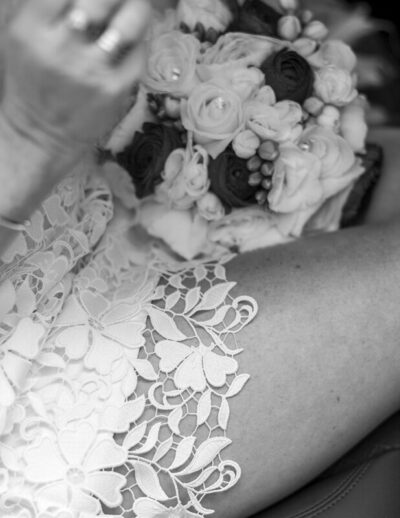 Gros plan sur la dentelle d'une robe de mariée et un bouquet de roses tenues avec tendresse