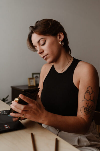 Femme tatouée concentrée sur son téléphone à un bureau minimaliste dans un cadre lifestyle épuré