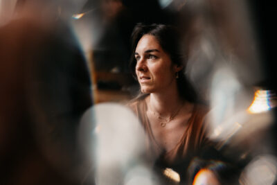 Femme brune regardant au loin, lumière chaude et reflets en bokeh encadrant son visage avec sérénité
