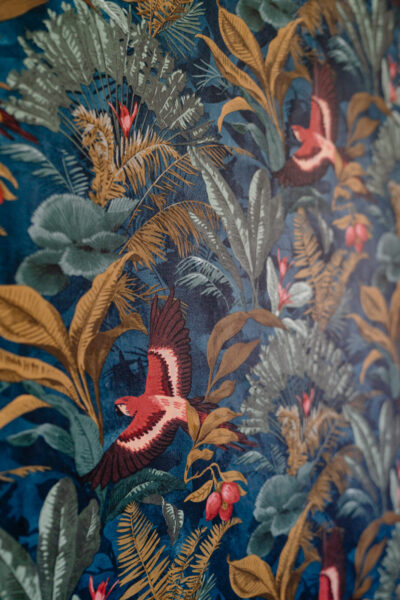 Tapisserie en velours bleu marine à motif tropical avec perroquets rouges et feuillage dense