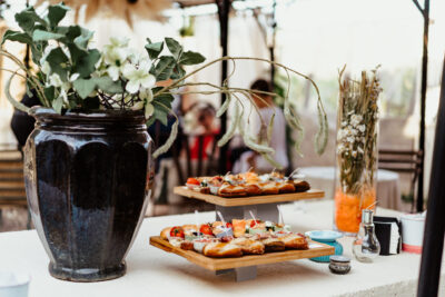 Table de cocktail avec planches de petits fours et vase floral dans un espace événementiel en plein air